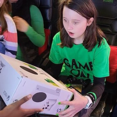 An image of our game bus client, getting a video game system as a gift from of their game bus birthday
