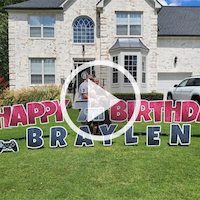 a video play button made from an image of our game bus client, standing in from of their birthday yard sign