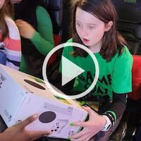 a video play button of a girl in a green shirt receiving her XBox gift included in our gaming birthday party package.