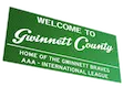 Green roads sign saying welcome to Gwinnett County / Gaming Truck Near Me. We Serve: Lawrenceville • Buford • Suwanee • Duluth